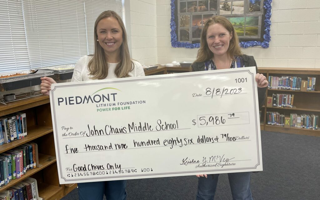 two smiling people holding an educational grant check